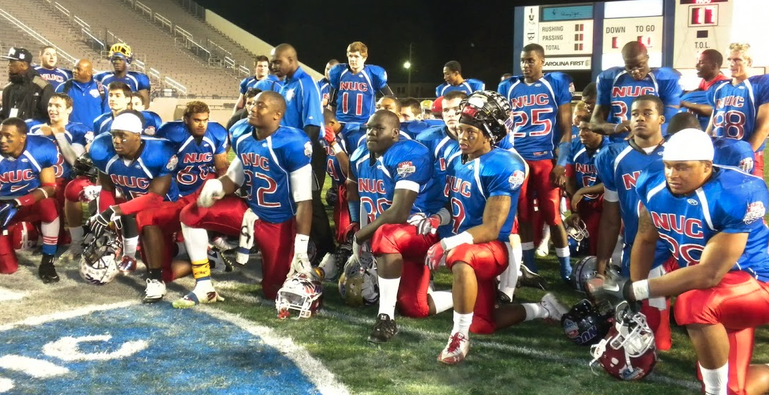 Team NUC kneeling together on the field during postgame ceremony