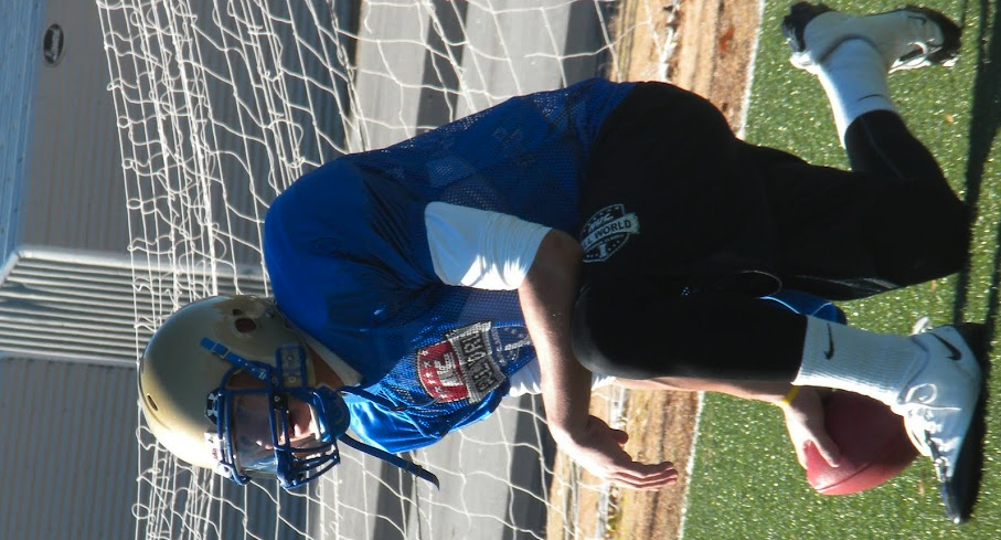 NUC All World player in blue jersey carrying the football on the field