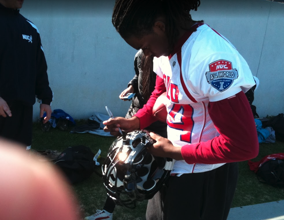 Female NUC All World player signing a helmet on the sideline