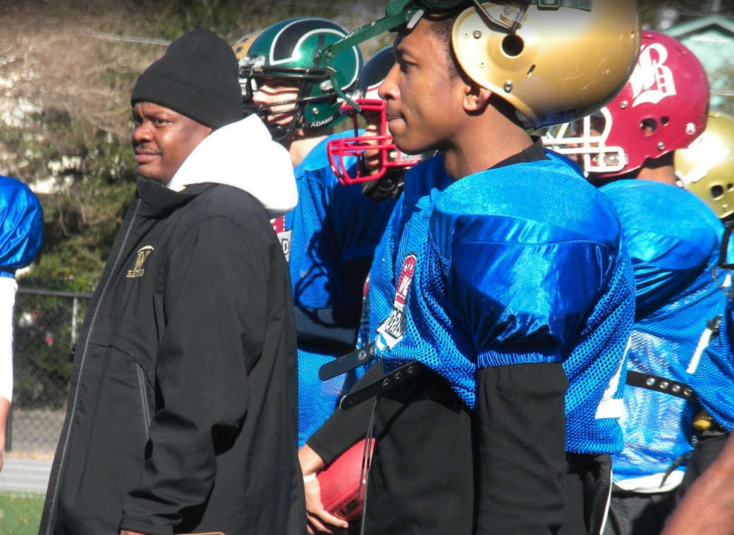NUC All World players and coach watching practice on the sideline